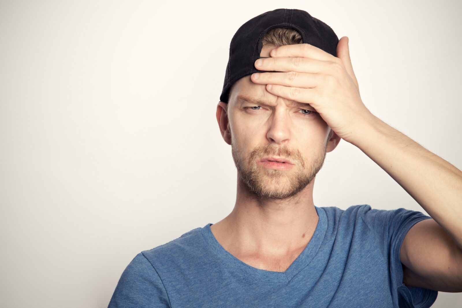 Person with hand on forehead experiencing head pain before migraine treatment Fairfax evaluation